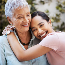 both caregiver and patient smiling while caregiver is hugging her patient