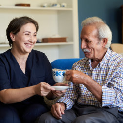 caregiver smiling at patient with coffee