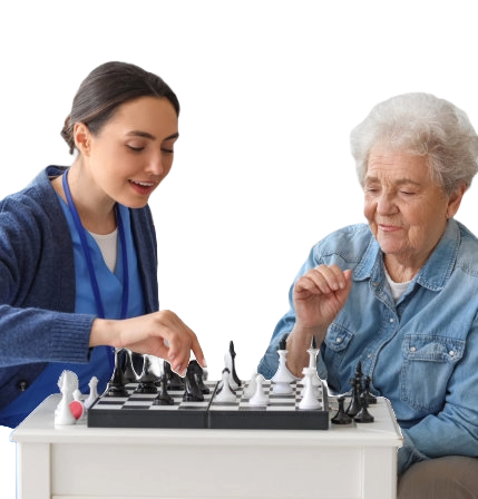 Young caregiver with senior woman playing chess at home