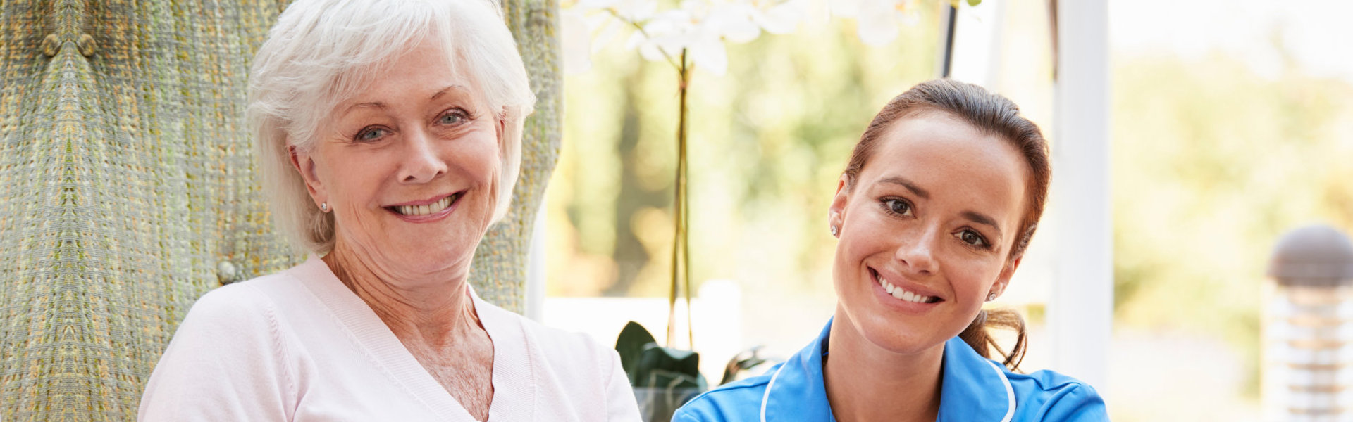 Portrait Of Senior Woman Sitting In Chair With Nurse