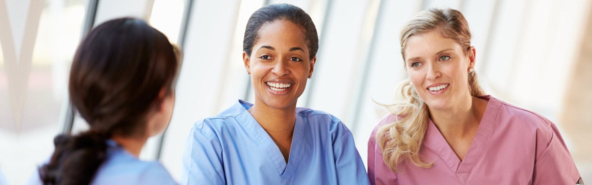 Group Of Nurses Chatting In Modern Hospital Canteen Smiling